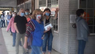 Clay County Election Board worker Linda Hagberg helps keep the line flowing during Thursday’s opening day of One-Stop voting in Hayesville. Lines of mostly masked voters stretched to the end of the sidewalk most of the day, at times inching around the corner of Church and Main.