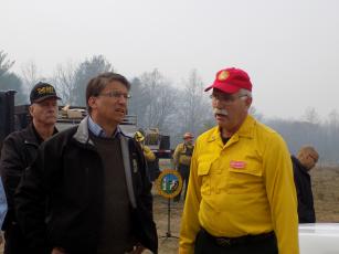 Progress photo by Lorrie Ross. Then Governor Pat McCrory flew in one early November Sunday morning to thank firefighters and meet with fire officials. After hearing a briefing, he visited several firefighters working Boteler Fire. McCrory on left, receives a briefing from Southern Area Red Team Operations Section Chief Steve Weaver. Vic Davis, Clay County Sheriff at the time, stands behind the men.
