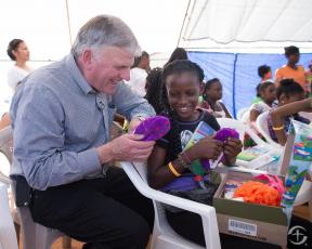  Franklin Graham watching as a young girl open her shoebox from Operation Christmas Child. (Photo courtesy of Samaritan’s Purse)