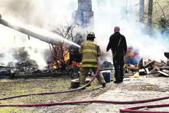 (Tyler Faggard • Clay County Sheriffs Office) A local deputy observes the burned debris while a firefighter tries to salvage and control a fire that engulfed a home on Fires Creek.