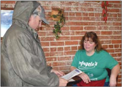 (Becky Long • Clay County Progress) Environmental Health Supervisor Joe Jack Sellers delivers a copy of an email his office received from Gov. Cooper to E.J. Caiazzo of Angelo’s Downtown Pizza explaining that only carry-out and delivery services are allowed in the state.