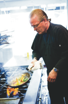 Photo submitted (Right) Dennis Barber, owner and chef at The Copper Door, prepares food for his award-winning restaurant in downtown Hayesville. This pre pandemic photo was taken prior to the strict restaurant guidelines being followed by Barber and staff.