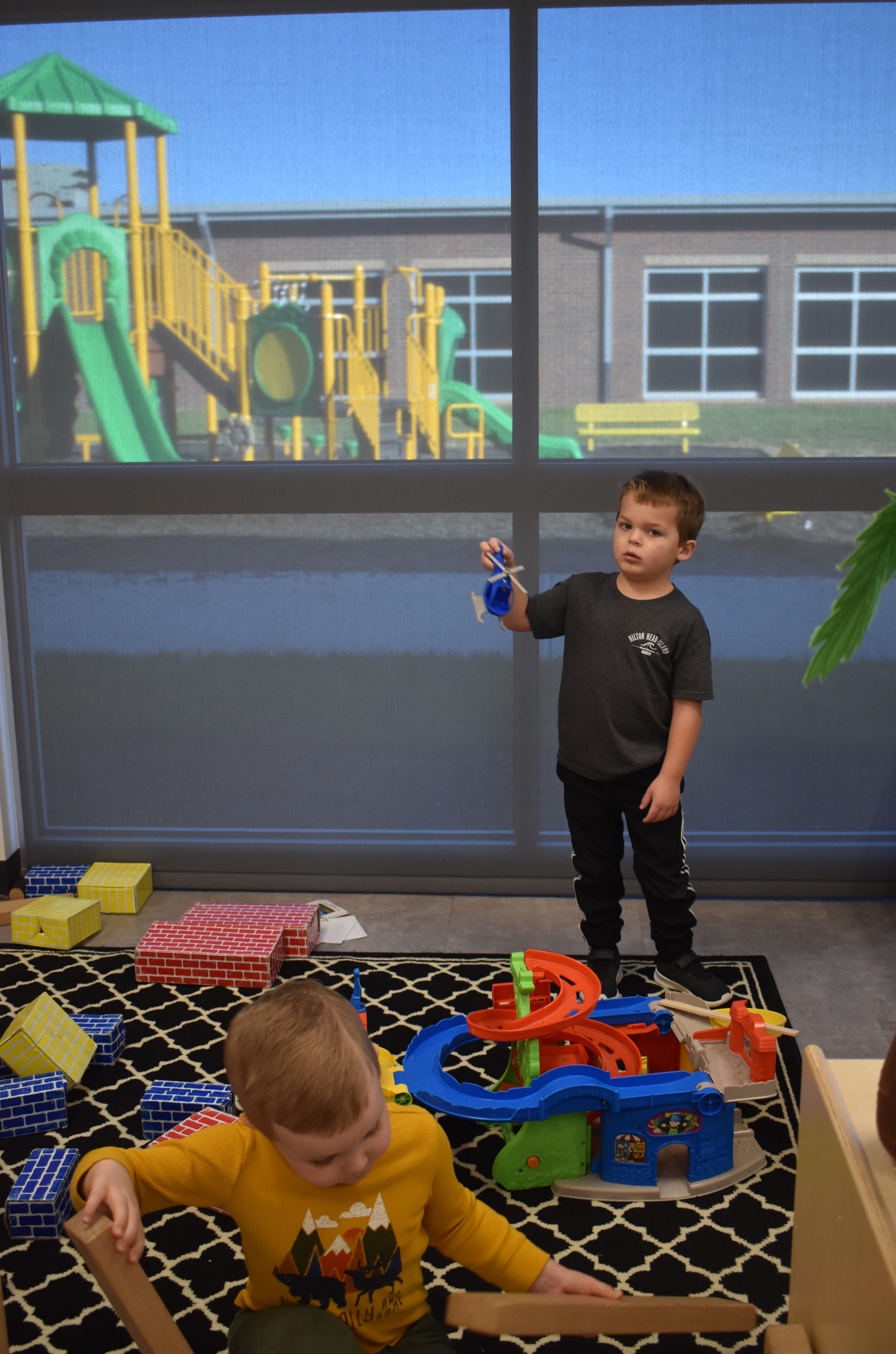 (Brittany Sullivan • Clay County Progress) Pre-K students’ Hudson Parker, seated, and Weston Reece enjoy activities in their learning centers in the new primary school. Reece bragged about his “amazing,” playground which is on the other side of the school. The first and second grade playground is shown in the background.