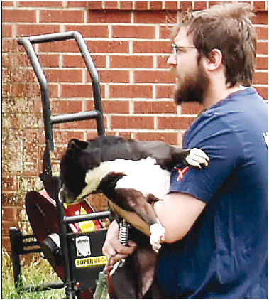 Becky Long • Clay County Progress Tylor Matheson reunites with the family dog, “Tudy,” which had been leashed to the front porch railing when the fire erupted. Deputy Tyler Faggard cut the leash to free the dog from the flames and smoke.