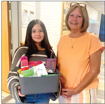 Sara Teleky, left, is presented a $50 cash prize and gift basket for entering the winning theme and illustration for the 2024 Hayesville Christmas Parade. Making the presentation is Clay County Progress publisher Becky Long.