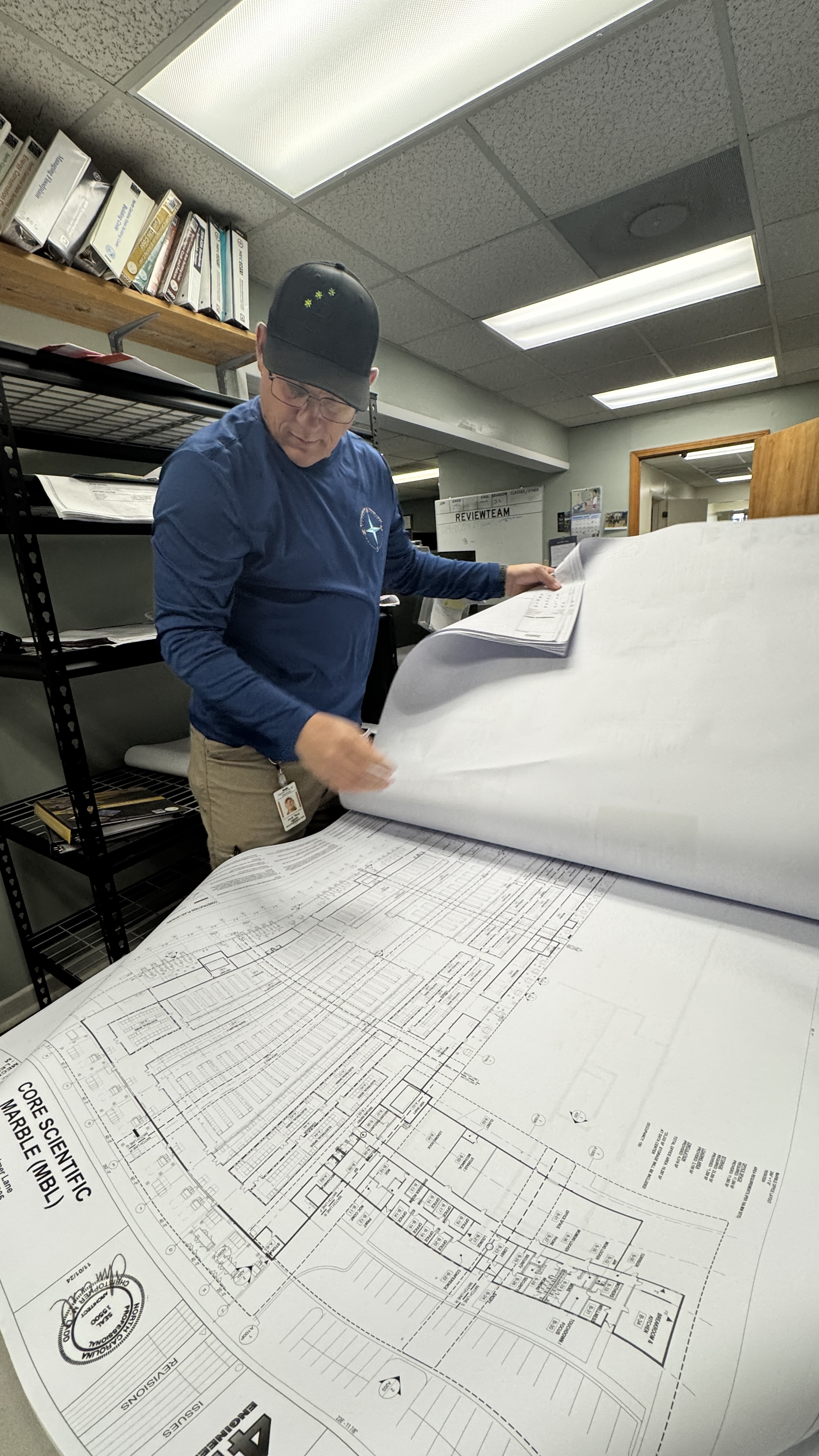 Randy Foster • editor@cherokeescout.com Cherokee County code enforcement official David Ricks sorts through half of about 50 pounds of site plans for an expansion project at Core Scientific in Marble on Monday.