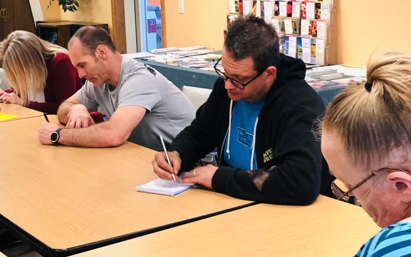 From left, Kristi and Darren Cook and Steven Donaldson take notes for an activity during the Community Café.