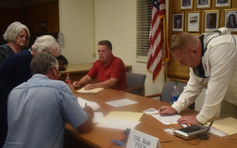 (Becky Long • Clay County Progress) County attorney Merinda Woody and administrator Betty Bradley wait for commissioners’ Dwight Penland, Scotty Penland and Rob Peck, along with Randy Nichols, not shown, to sign resolutions following the Oct. 1 county commission meeting. Commissioner Clay Logan was not present.