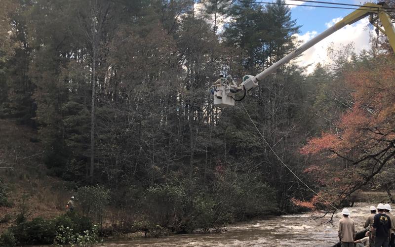 A Blue Ridge Mountain EMC crew pulls a tap line across the Toccoa River in Suches, Ga. at Cavender Gap and Highway 60. Lineman Chase Hemphill is in the bucket while crewmen Kelly Cruse, Clayton Wood, Jeff Odom, Terrence Kane, Chris Busbee, Jesse Miller and Josh Bryant wait to finish their duties after the tap line gets across the river.