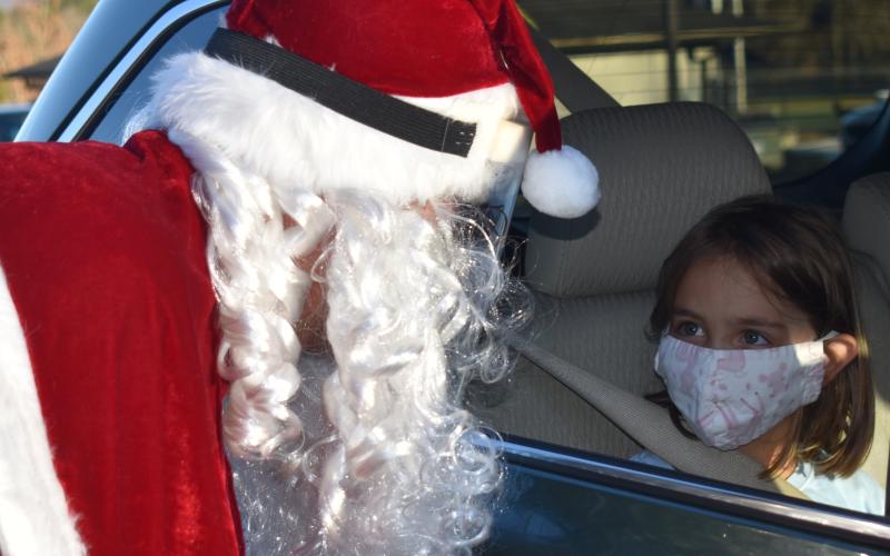 Lotte Jones, 5, gazes into Santa’s eyes during his recent visit to the Clay County Schools campus. Like Jones, numerous children greeted the jolly good man via a drive-thru visit hosted by the school. They received treats and dropped off their wish lists. Santa shared his list with the newspaper this week. Letters to Santa from our schools’ Pre-K through second grades appear in this edition’s C section, along with more photos from the drive-thru visit with Santa.