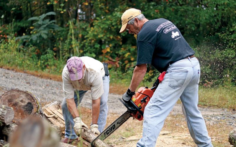 Volunteer woodchuckers Glynn Bourque  and Ricky Beggs cut donated wood for Hinton’s Firewood Ministry.