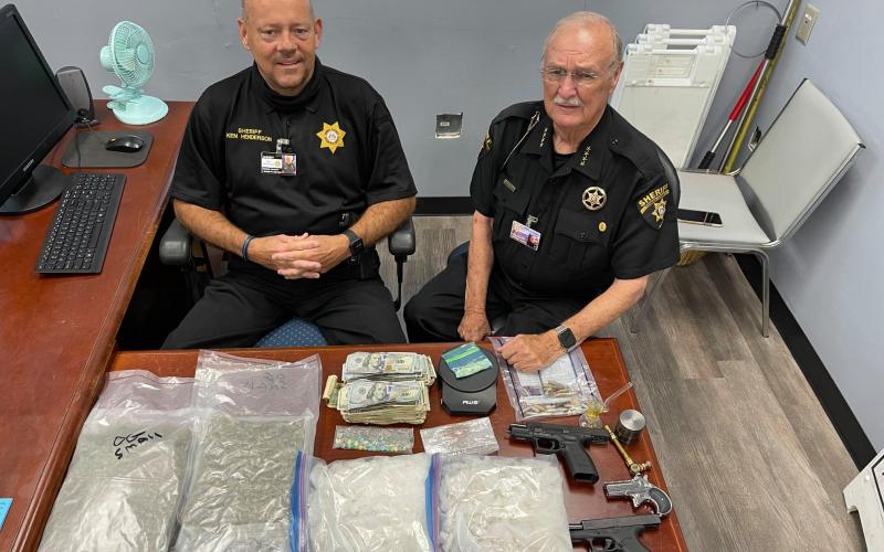 Towns County Sheriff Ken Henderson and Chief Deputy Gene Moss display drugs, guns and cash seized in the June 17 bust. Henderson praised the Sheriff’s Drug Investigative unit and deputies who he said put in long hours on these investigations.