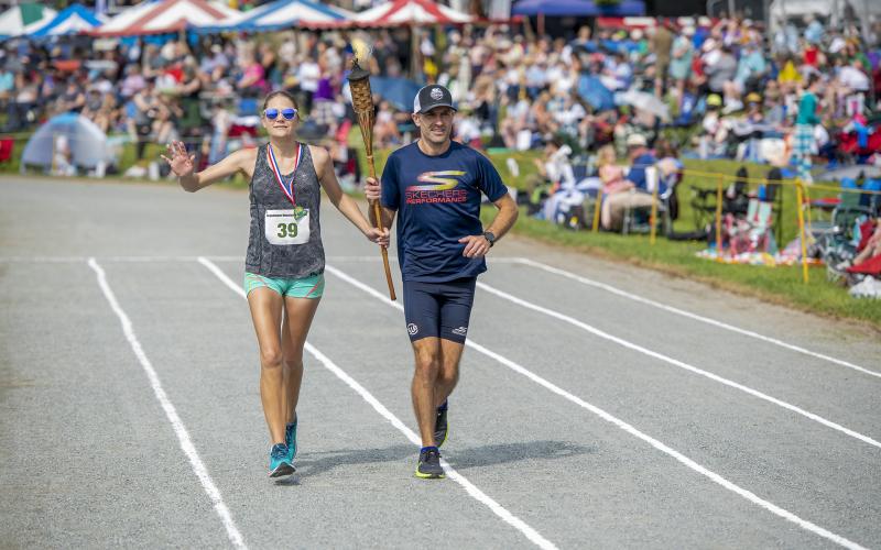 (Photo by Skip Sickler | Grandfather Mountain Stewardship Foundation)  Maggie Fortney and Caleb Masland make their victory lap at MacRae Meadows, site of the annual Grandfather Mountain Highland Games, after completing the 53rd Grandfather Mountain Marathon Saturday, July 10. Masland finished first with a time of 2:48:37.2, while Fortney was the first female finisher and ninth overall with a time of 3:31:18.6.