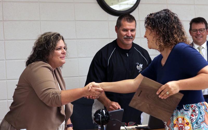 (Jared Putnam • Clay County Progress) From left, Clay County Board of Education member Kelly Crawford shakes hands with Emily Mull, Clay County Schools' Teacher of the Year, while board chairperson Jason Shook and Superintendent Dale Cole look on during the June meeting on Monday in Hayesville.