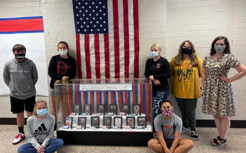 From left, Elijah Mayfield, Mandy Pendergrass, Kinleigh Queen, Americas LeQuire, Kaylin Ellis, Macie Postell and history teacher Nicole Hedden next to a memorial in honor of the 13 service members killed in Kabul last month. Students who helped with the exhibit but not pictured are Makayla Whitehead, Michael Samten, Madison Cogdill, Marlee Postell, Bronson Ludixen, Brianna Downs and O’Ryan Brockwell.