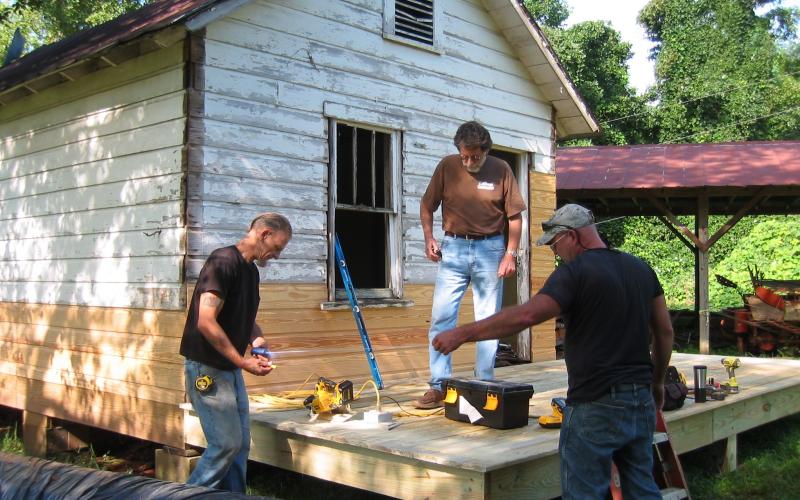 Tommy Davis of Woodhaven Construction, center, consults with carpenters Jeremiah Burch, left and David Collins, right, for replacing  damaged wood on the 1930s Hayesville Town Hall building as a classroom with porch added for outdoor presentations.