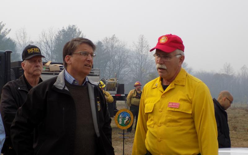 Progress photo by Lorrie Ross. Then Governor Pat McCrory flew in one early November Sunday morning to thank firefighters and meet with fire officials. After hearing a briefing, he visited several firefighters working Boteler Fire. McCrory on left, receives a briefing from Southern Area Red Team Operations Section Chief Steve Weaver. Vic Davis, Clay County Sheriff at the time, stands behind the men.