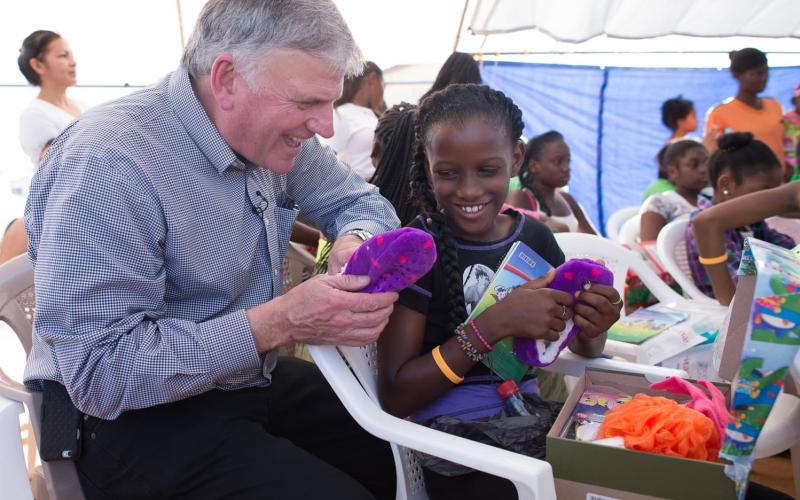 Franklin Graham watching as a young girl open her shoebox from Operation Christmas Child. (Photo courtesy of Samaritan’s Purse)