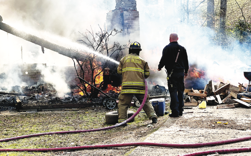 (Tyler Faggard • Clay County Sheriffs Office) A local deputy observes the burned debris while a firefighter tries to salvage and control a fire that engulfed a home on Fires Creek.