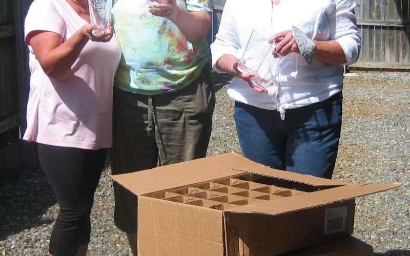 Historic Hayesville Inc. volunteers Surbrinia Baumgartner, Paula Walters and Vicky Donaldson have signature glasses ready for the 8th annual Steins &amp; Wine event. Logo beer glasses are sponsored by Sonja Silvers Realty and wine glasses are donated each year by Advantage Chatuge Realty.