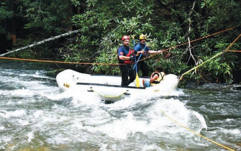 Joe Davenport • Clay County Progress A Valley Town Swift Water Rescue team member and Clay County Fire &amp; Rescue’s Tim Noland  transport a young boy who had been stranded back to the safety of dry ground