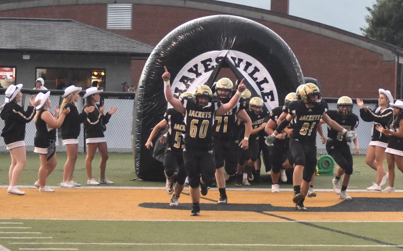Gary Corsair • Clay County Progress Lane Odell, 61; Zek Furby, 71, and Maverick Imlay, 81, lead the Hayesville Yellow Jackets out of the tunnel and into the 2022 varsity football season.