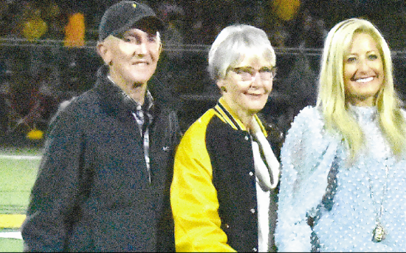 Gary Corsair • Clay County Progress Parents Steve and Jan join Julie Stackhouse on the football field during a halftime ceremony marking her record-holding accomplishments at Hayesville High School.