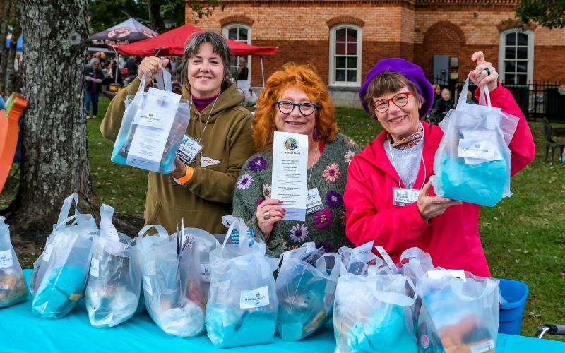 Photo • Ron Wallace HHI Volunteers, from left,  Misti Muscat, Lynne Maniotes and Wendy Slaton hold up gift bags for attendees to use as they enjoy wine, beer, food or items from crafty vendors during the annual Steins &amp; Wine event.
