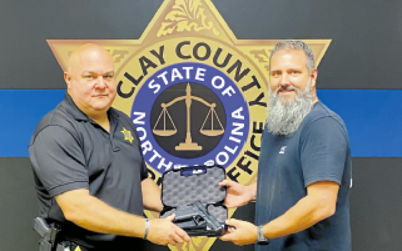 Investigator Todd Wingate conducts the traditional transfer of the firearm and badge worn by  Sheriff Bobby Deese.