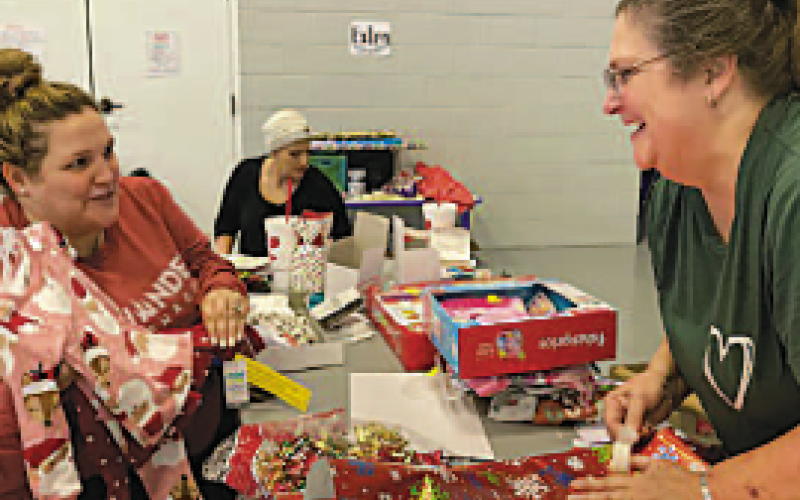 Lauren Tucker, left, shows Project Director Karen Coker baby sleepwear she is about to wrap during a gift wrapping event on Saturday, Dec. 10 at Catalyst Church in Hayesville.