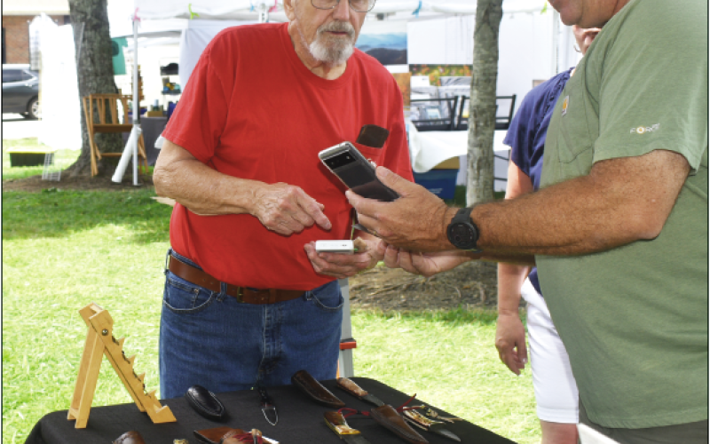 Becky Long • Clay County Progress Mike Wilson, left, of Wilson Custom Knives conducts an electronic sale with a customer during Sunday’s Festival on the Square. Wilson is a long-time vendor at the annual festival. He set up his knife shop here in 2000, the same year he moved to Hayesville.