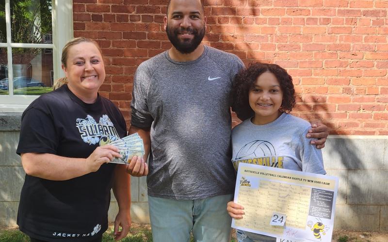Coach Tammy Dills, left, presents the $500 cash winnings to Rick Jackson after choosing a date from Kaydence Morrow’s, board in the Hayesville volleyball program calendar raffle.