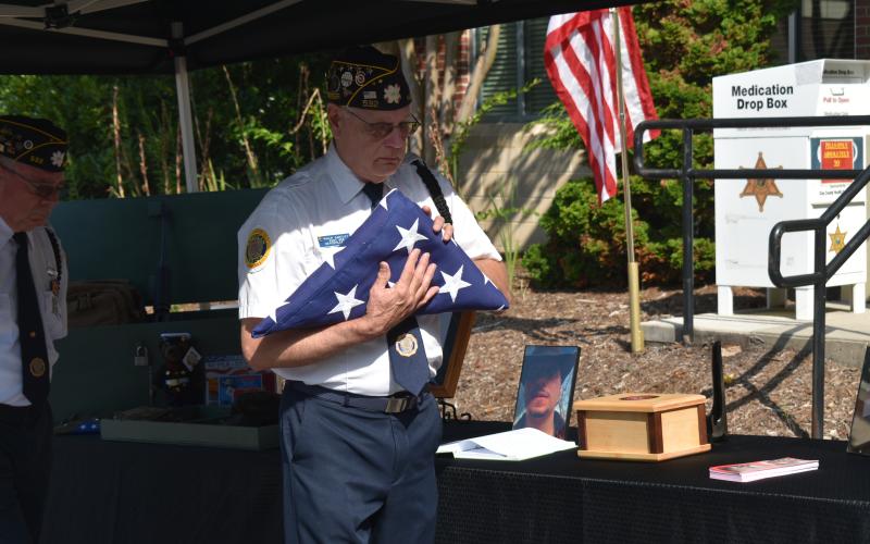 Becky Long • Clay County Progress American Legion member Phil Cantley prepares to place the U.S. Flag near Marine Lance Corporal Sean Willey’s remains on the memorial table which also displayed a photo of Willey that had been posted in March 2022, a month before he is believed to have died.