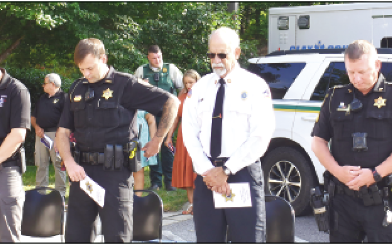 Becky Long • Clay County Progress Emergency responders bow their heads during prayer at the 911 ceremony at the Clay County Sheriff’s Office. They are, from left, 911 Director Kevin Sellers, EMS Community Paramedic Ben English, Law enforcement deputy T.J. Major, Fire &amp; Rescue Battalion Chief Pete Trocchia and Corporal Will Suggs, representing military divisions. The Patriots Day program honored the hundreds of emergency workers who lost their lives on 9/11.