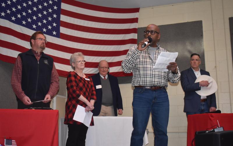 Becky Long • Clay County Progress Fort Hembree Pastor Harold Holbrook Jr., center, opens Saturday’s debate with prayer. He is joined on stage by, from left, U.S. Rep. Chuck Edwards, Clay County Republican Chairperson Barbara Deas, moderator Larry Ford and congressional primary candidate Christian Reagan. The venue for the debate was Brasstown Community Center which holds about 165 people and was filled to near capacity.