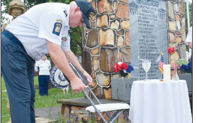 Incoming VFW Commander John Clodfelter places the POW MIA fl ag at the memorial honor table.