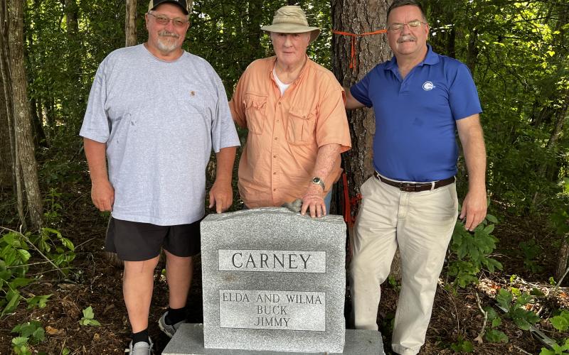 Deby Jo Ferguson • Clay County Progress Danny Jones, Ken Ball and Andy Gibson stand at the grave marker that distinguishes where the remains of the Carney family, Elda, Wilma, Buck and Jimmy are now buried together.
