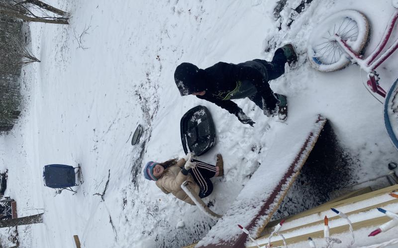 Payton and Jacob Taylor find a small hill to go down using a trash can lid as a make shift sled