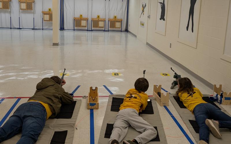 From left, Devin Ramey, Masyn Parrinello and Zoe Angelopulos compete in the prone position at the air rifle competition.