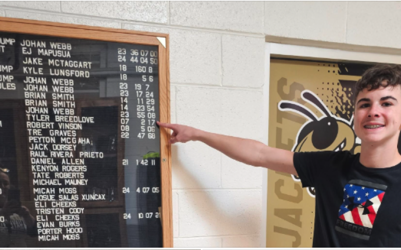 Eli Cheeks points to Tyler Breedlove’s record-setting time on display at the school. Cheeks has now set his own record in the 800 meter run.