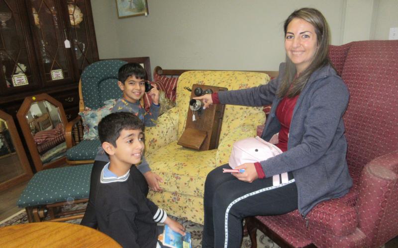 Aiden and Ryan Behnia took time with their mom Asa to  see how to make a call with an antique home phone in the Trash to Treasure showroom.