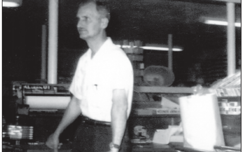M.C. “Babe” Moore is shown at the check out counter in his store location featuring everything from groceries to family merchandise and gas pumps at a busy crossroads.