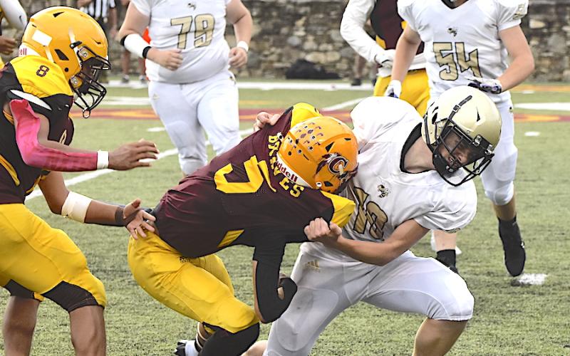 Gary Corsair • Clay County Progress Hayesville's Dustin Lockaby, No. 11, puts a headlock on a Cherokee bar carrier as teammates Devin Ramey, No. 54, and Mason Parker, No. 79, come to help.