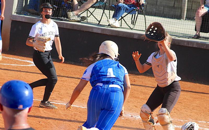 Hayesville catch Caroline Wade focuses on the throw home as a base runner bears down on the plate while Micalynn McClure backs up the play. Photo by Neal Wachob.