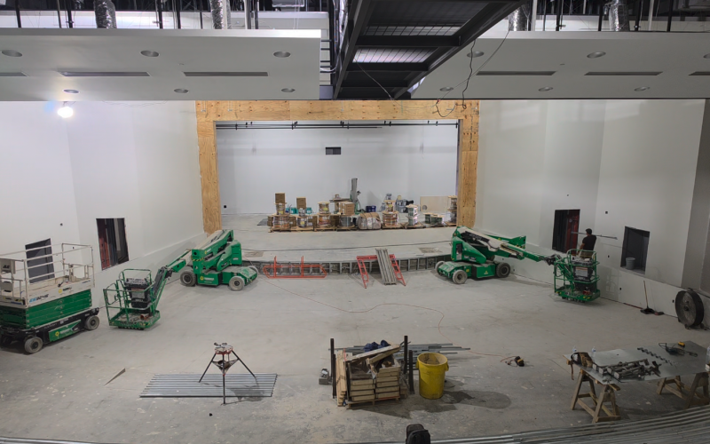 An interior look at the new auditorium shows the base for tiered seating, catwalk at the top of photo ready for paint and work continuing around stage area.