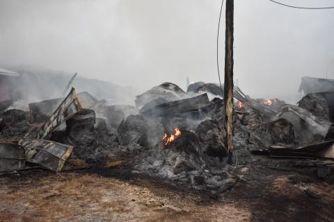 Hundreds of bales of hay smolder hours after the initial spark sent this hay barn up in flames.  (Progress photo by Travis Dockery) 