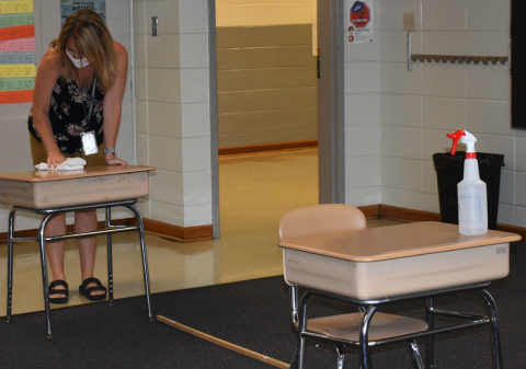 Brittany Sullivan • Clay County Progress Hayesville Elementary fourth grade teacher Keisha McClure helps organize the classroom and sanitize desks in anticipation of the new school year which officially starts Aug. 17. The ruler on the floor illustrates the 6-feet marker required between each student’s desk. This year Hayesville schools will be operating on a two-day face-to-face instruction procedure with the other three days set aside for remote learning. 