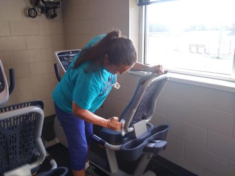 (Travis Dockery • Clay County Progress) Gym member Debra Bolle cleans a machine after her first workout since the reopening. Bolle was the first person to join the gym when it initially opened. 