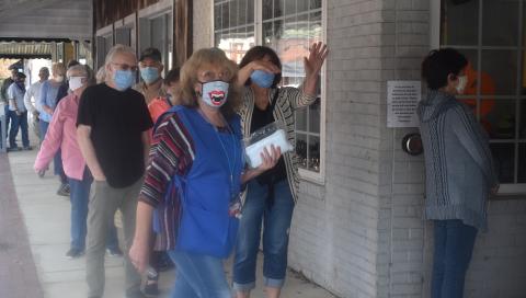 Clay County Election Board worker Linda Hagberg helps keep the line flowing during Thursday’s opening day of One-Stop voting in Hayesville. Lines of mostly masked voters stretched to the end of the sidewalk most of the day, at times inching around the corner of Church and Main.