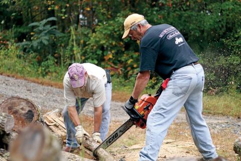 Volunteer woodchuckers Glynn Bourque  and Ricky Beggs cut donated wood for Hinton’s Firewood Ministry.
